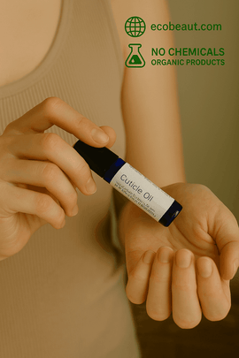 Woman applying Butter Me Up Organics Cuticle Oil with a roll-on bottle to her fingernails. Natural and chemical-free nail care with ecobeaut.com branding in the top corner.