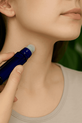 "Woman applying custom perfume oil from a cobalt blue roll-on bottle to her neck, with green leaves, black eco labels, and ecobeaut.com branding in the top right corner."