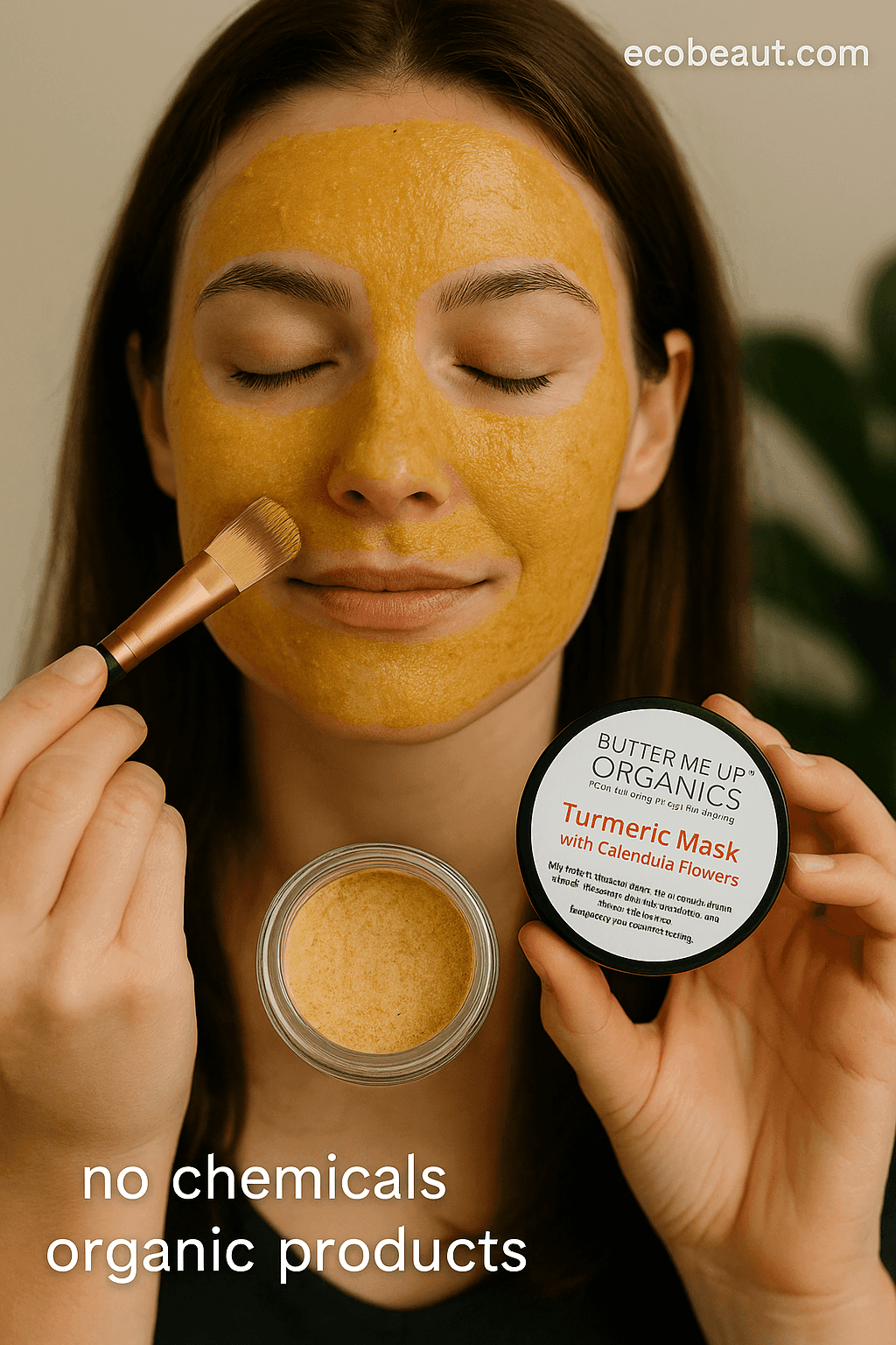 Woman applying turmeric mask with calendula flowers on her face using a brush, holding a jar labeled Butter Me Up Organics, with 'no chemicals' and 'organic products' icons and ecobeaut.com in the top right corner