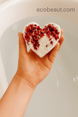 Woman holding a heart-shaped rose bath bomb above the bathtub – eco-friendly skincare by ecobeaut.com