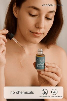 Young woman applying Eucalyptus & Spearmint Body Elixir to her chest using a dropper, holding the green bottle labeled "A Girl's Gotta Spa!", with eco-friendly icons and ecobeaut.com in the top right corner