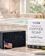 Bar of coffee soap with packaging on a bathroom counter
