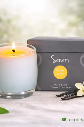 Sanari candle with packaging and vanilla beans on a light surface