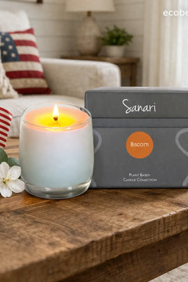 Lit candle in a decorative container next to a gray box labeled 'Sanari' on a wooden surface.